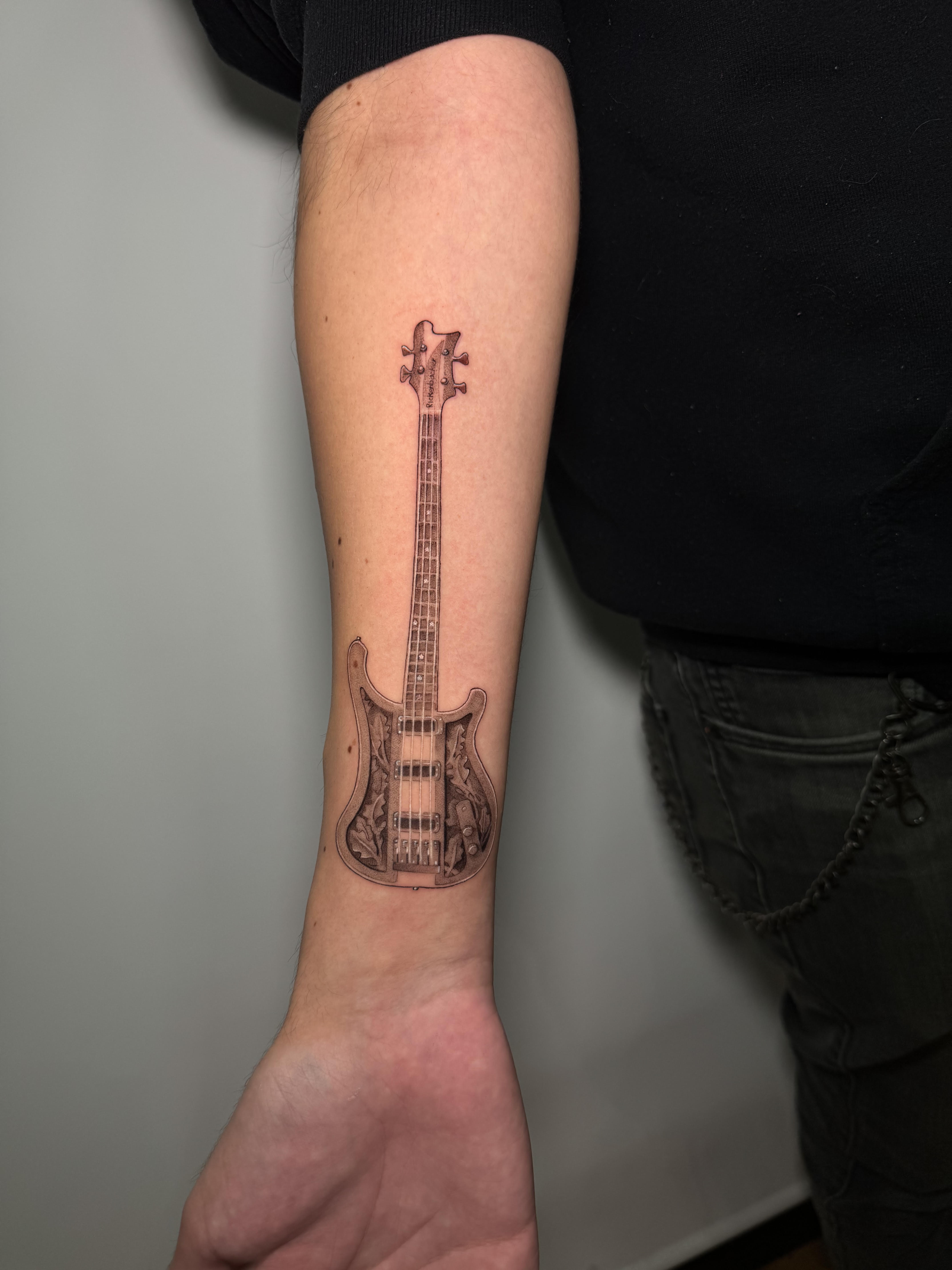 Tatuaje bajo Rickenbacker microrealismo en antebrazo — CAOS Art Tattoo Chile
