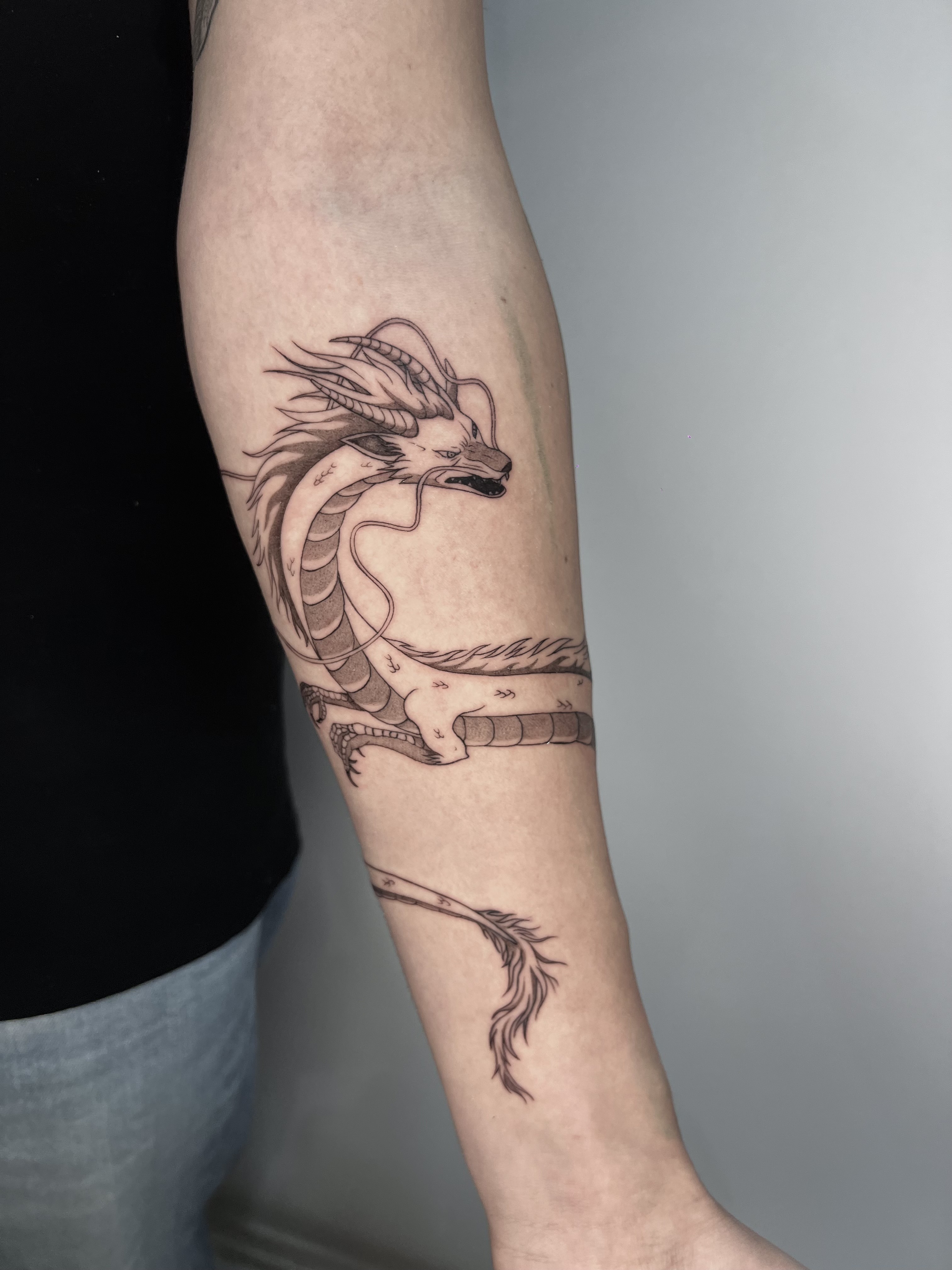 Tatuaje dragón lineal blackwork antebrazo — CAOS Art Tattoo Chile