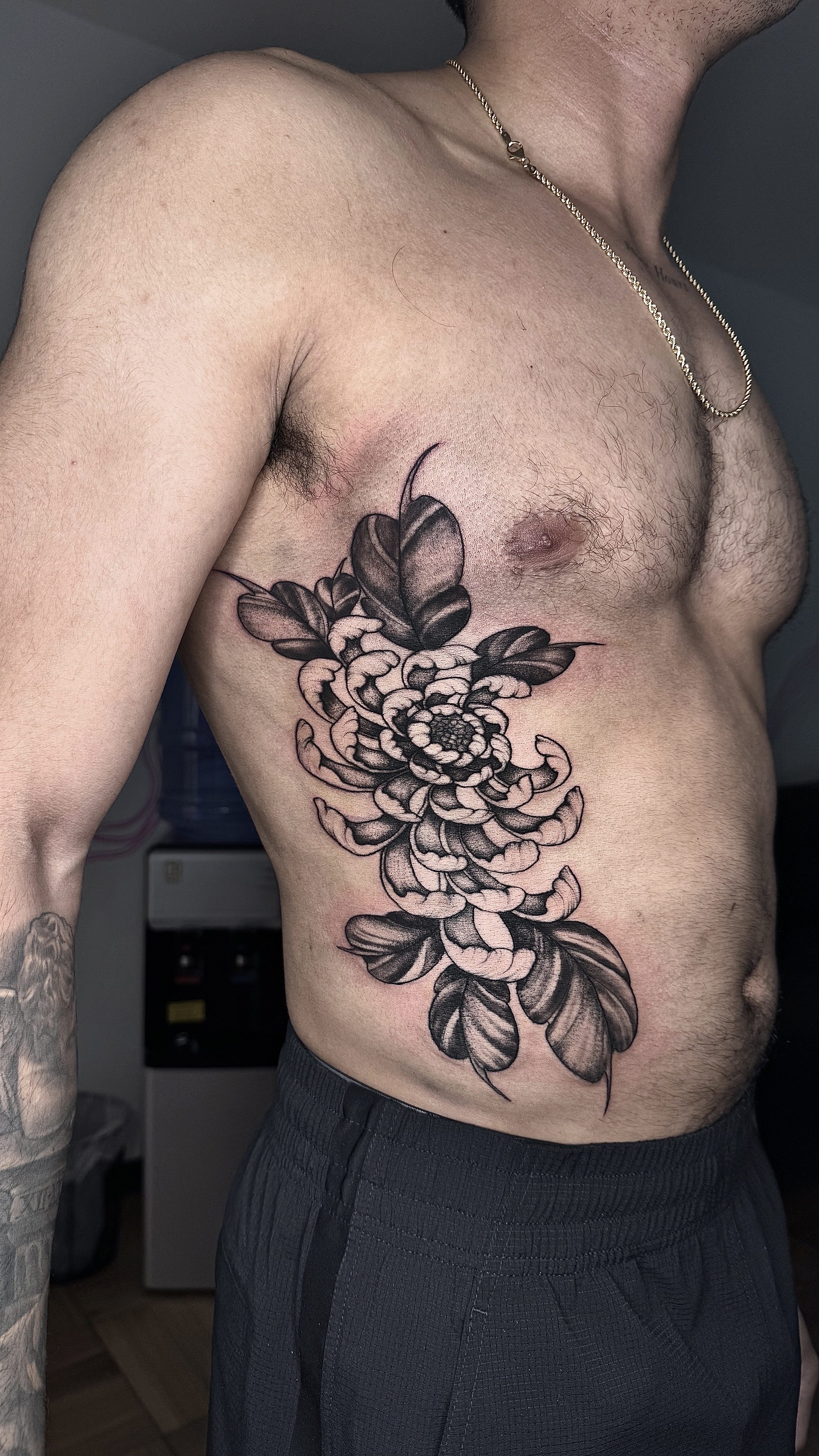 Tatuaje crisantemo blackwork costado torso — CAOS Art Tattoo Chile